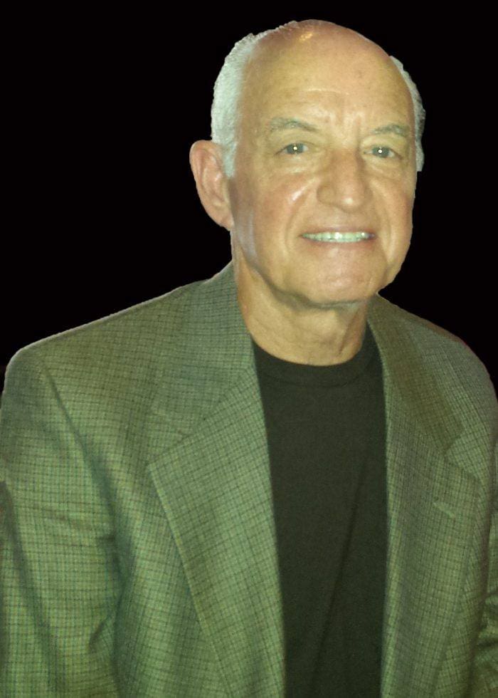 A man in a green jacket and black shirt.